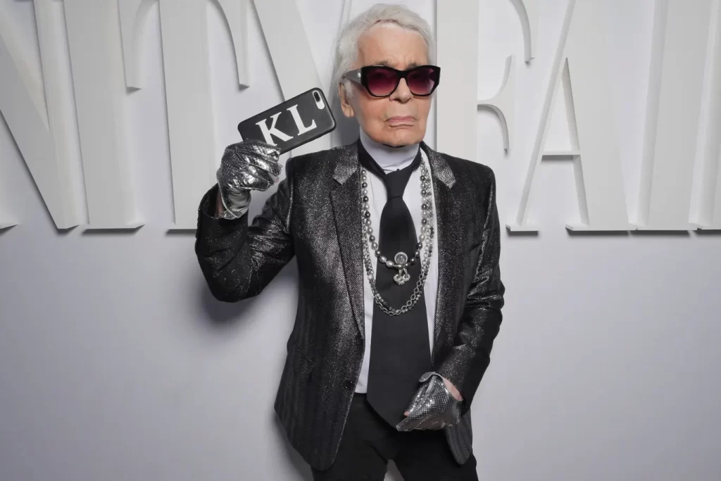 کارل لاگرفلد به همراه یک کت براق و اکسسوری‌های نقره‌ای بزرگ